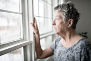 Older woman looks out a window